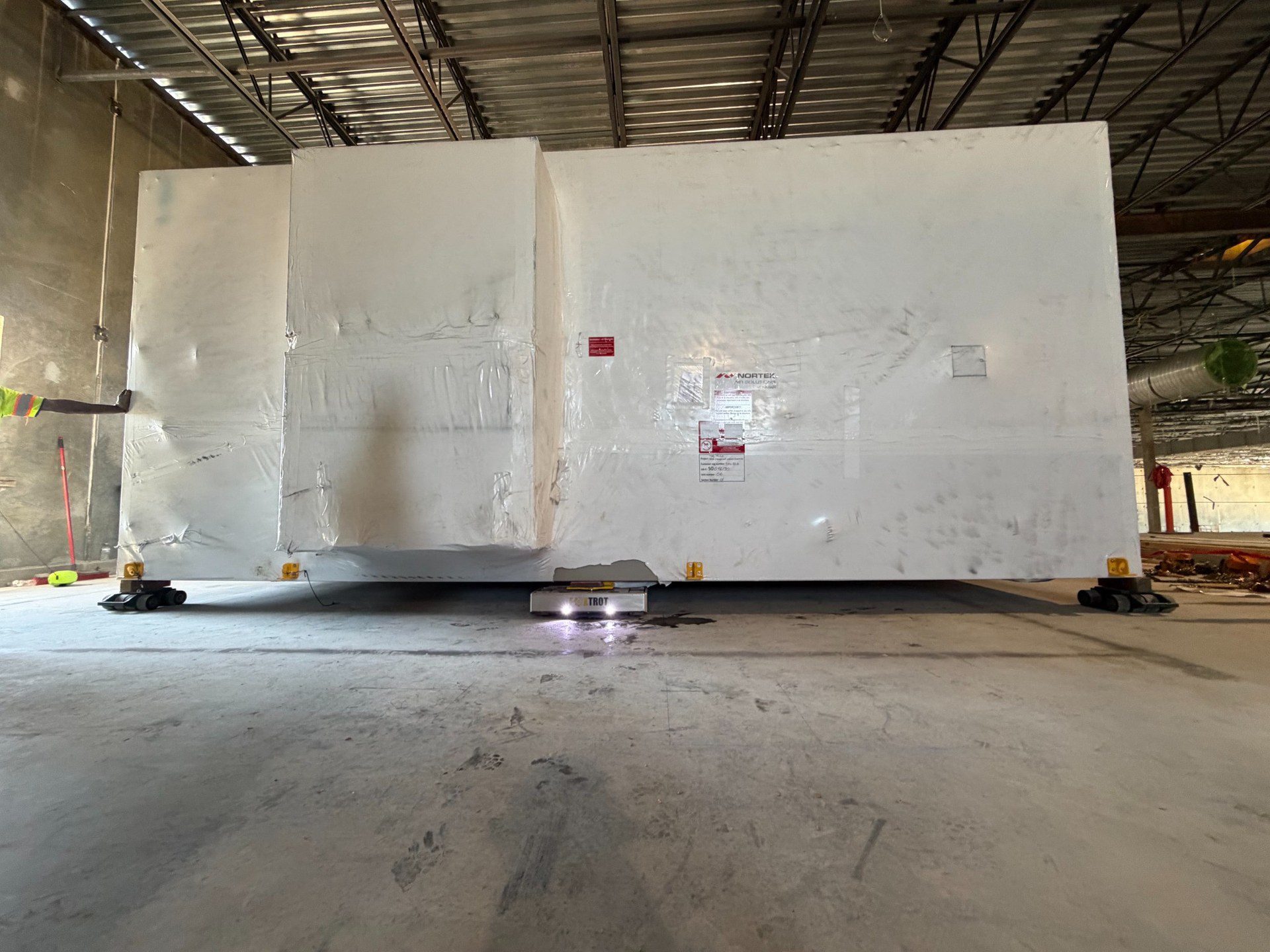 How Valor Specialized Rigging Moved a 15,000 lb Air Handler with a Hoist FR 40/60 Wrapped Nortek air handler resting on machinery skates with a powered unit centered beneath it